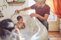 Père donnant père ludique donnant bain filles tout-petits — Photo de stock