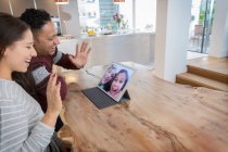 Щасливі батьки відеоконференції з дочками на цифровому планшеті на кухні — стокове фото