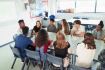 High school students talking in debate class at table in classroom — Stock Photo