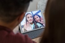 Дочери на цифровом планшете машут родителям, видеоконференции с родителями — стоковое фото