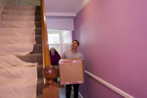 Happy couple moving into new house, carrying cardboard boxes in corridor — Stock Photo