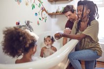 Parents giving toddler daughters bubble bath — Stock Photo