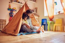 Father and toddler daughter reading book in teepee — Stock Photo