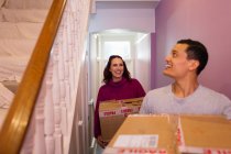 Happy couple moving into new house, carrying cardboard boxes in corridor — Stock Photo