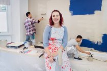 Portrait confident woman in overalls painting room with friends — Stock Photo