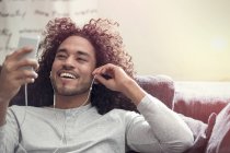 Усміхнений молодий чоловік слухає музику з навушниками та mp3 плеєром — стокове фото