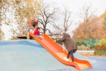 Grandparents playing with grandson on playground slide — Stock Photo