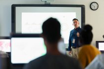 Male junior high teacher leading lesson at projection screen in classroom — Stock Photo