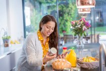 Улыбающаяся женщина с цифровыми таблетками выпечки на кухне — стоковое фото