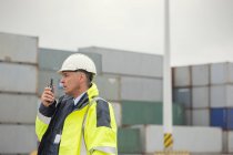 Hafenmanager mit Walkie-Talkie zwischen Frachtcontainern auf der Werft — Stockfoto