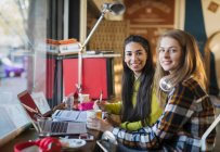 Retrato sonriente estudiantes universitarias que estudian en el ordenador portátil en la cafetería - foto de stock