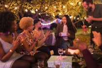 Friends surprising woman with gift at garden birthday party — Stock Photo