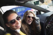 Porträt glückliche, verspielte junge Frauen mit Sonnenbrille im Auto — Stockfoto