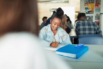 High school girl student doing homework at table in classroom — Stock Photo