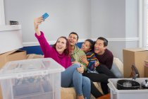 Amigos felizes fazendo uma pausa de se mover, tirando selfie no sofá — Fotografia de Stock