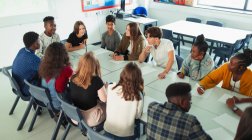 Estudantes do ensino médio conversando à mesa em aula de debate — Fotografia de Stock