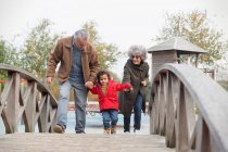 Grandparents walking with grandson on footbridge — Stock Photo