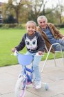 Портрет улыбающейся внучки на велосипеде с дедушкой в парке — стоковое фото