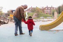 Großvater spaziert mit Kleinkind-Enkel auf Spielplatz — Stockfoto