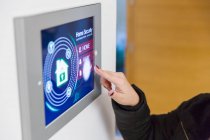 Woman setting smart home security alarm at touch screen — Stock Photo