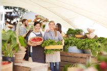 Портрет улыбающихся женщин с овощами на фермерском рынке — стоковое фото
