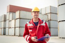 Porträt selbstbewusster Hafenarbeiter mit Klemmbrett und Walkie-Talkie auf der Werft — Stockfoto