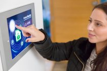 Frau stellt Smart-Home-Sicherheitsalarm am Touchscreen ein — Stockfoto