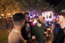 Мужчины разговаривают и пьют на вечеринке в саду — стоковое фото