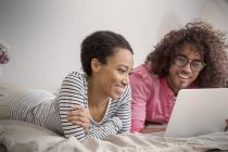 Casal sorrindo usando laptop na cama — Fotografia de Stock