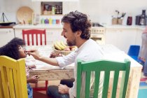 Vater füttert Tochter am Küchentisch mit Trauben — Stockfoto