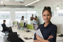 Retrato mujer de negocios con confianza con tableta digital en la oficina de planta abierta - foto de stock
