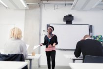 Lächelnde, glückliche weibliche Gemeinschaftsschullehrerin leitet Unterricht im Klassenzimmer — Stockfoto