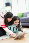 Irmãs usando tablet digital no chão da sala de estar — Fotografia de Stock