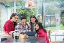 Щаслива сім'я використовує цифровий планшет за кухонним столом — стокове фото