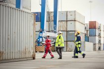 Dock workers walking along cargo containers at shipyard — Stock Photo
