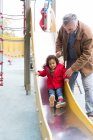 Avô brincando com neto da criança no diapositivo do playground — Fotografia de Stock