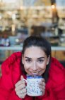 Porträt lächelt, selbstbewusste junge Frau trinkt Kaffee im Café-Fenster — Stockfoto