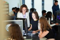 Жінка молодший викладач допомагає студенту-дівчинці за комп'ютером у комп'ютерній лабораторії — стокове фото