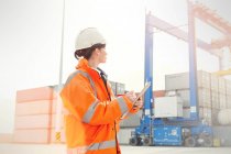 Female dock manager with clipboard watching cargo containers — Stock Photo