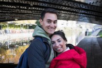 Ritratto felice giovane coppia che abbraccia lungo il canale — Foto stock