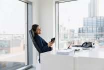 Smiling businesswoman using smart phone in urban office — Stock Photo