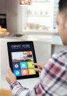 Чоловік контролює інтелектуальну систему навігації домом з цифрового планшета на кухні — стокове фото