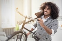 Jeune homme souriant portant un vélo — Photo de stock