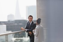 Business people talking and drinking coffee on sunny, urban balcony — Stock Photo