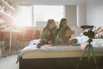 Adolescentes vlogging sobre maquiagem na cama no quarto ensolarado — Fotografia de Stock