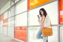 Молода жінка використовує смартфон на вокзалі — стокове фото