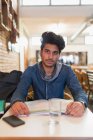 Portrait confident young male college student studying at cafe table — Stock Photo