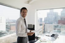 Portrait confident businessman with paperwork in urban office — Stock Photo