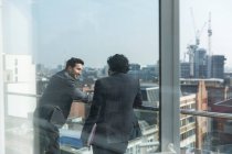 Бізнесмени говорять на сонячному, міському балконі — стокове фото