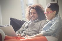 Couple relaxing, using laptop on sofa — Stock Photo